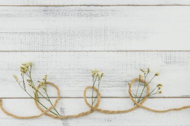 Kahverengi ip süslemeleri kopya alanı Beyaz ahşap zemin üzerine sarı limonium caspia çiçekli