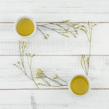 Sarı limonium caspia çiçeklerle kopya alanı Beyaz ahşap zemin üzerine çay bardak