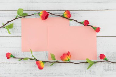 İki boş pembe kart sahte kırmızı çiçek dallarda beyaz tahta arka plan ile dekore edilmiş 