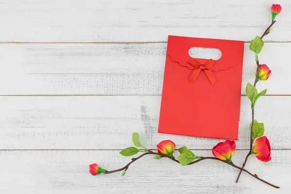 コピー スペースを持つ木材白地偽赤花枝と赤いギフト バッグ — ストック写真