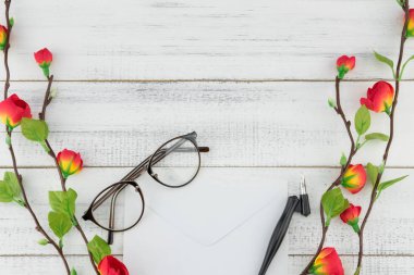 Beyaz örtmek, eğik kalem ve sahte kırmızı çiçek dallarda beyaz tahta arka plan kopya alanı ile süslenmiş gözlük