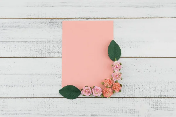 ピンクのバラの紙の花と空のピンクのカードを飾るし 木材が白地に緑の葉 — ストック写真