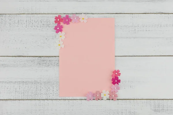 ピンクのダミーカードを飾る木白地にピンクの紙の花 — ストック写真