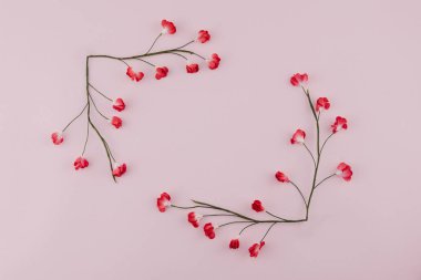 Kare çelenk şube kopya alanı ile pembe arka plan üzerinde kırmızı kağıt çiçeklerle yapılan