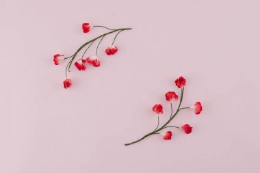 Şube kopya alanı ile pembe arka plan üzerinde kırmızı kağıt çiçeklerle yapılan yuvarlak çelenk