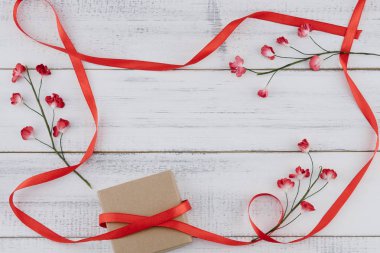 Kahverengi kutu süslemeleri ile kırmızı kağıt çiçekler ve kırmızı kurdele beyaz tahta arka plan ile kopya alanı üzerinde