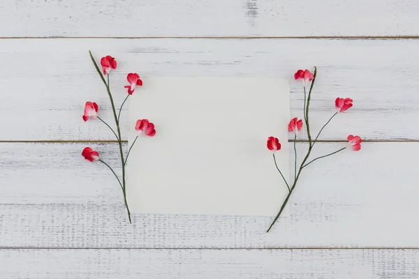 空白の白いカードを飾る白いウッドの背景に赤の紙の花 — ストック写真