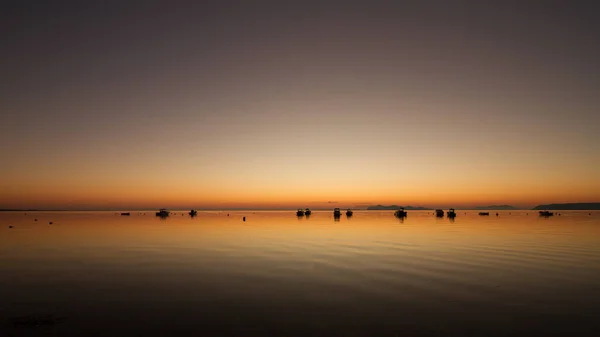 Um pôr-do-sol quente em uma água calma, com ilhas no fundo — Fotografia de Stock