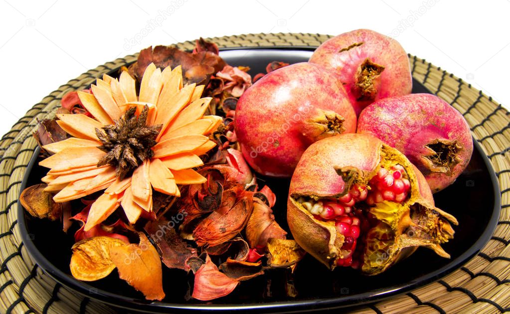 Dry flowers, potpourri and pomegranates on a black disk and wooden plate. For wellness and relaxing concept