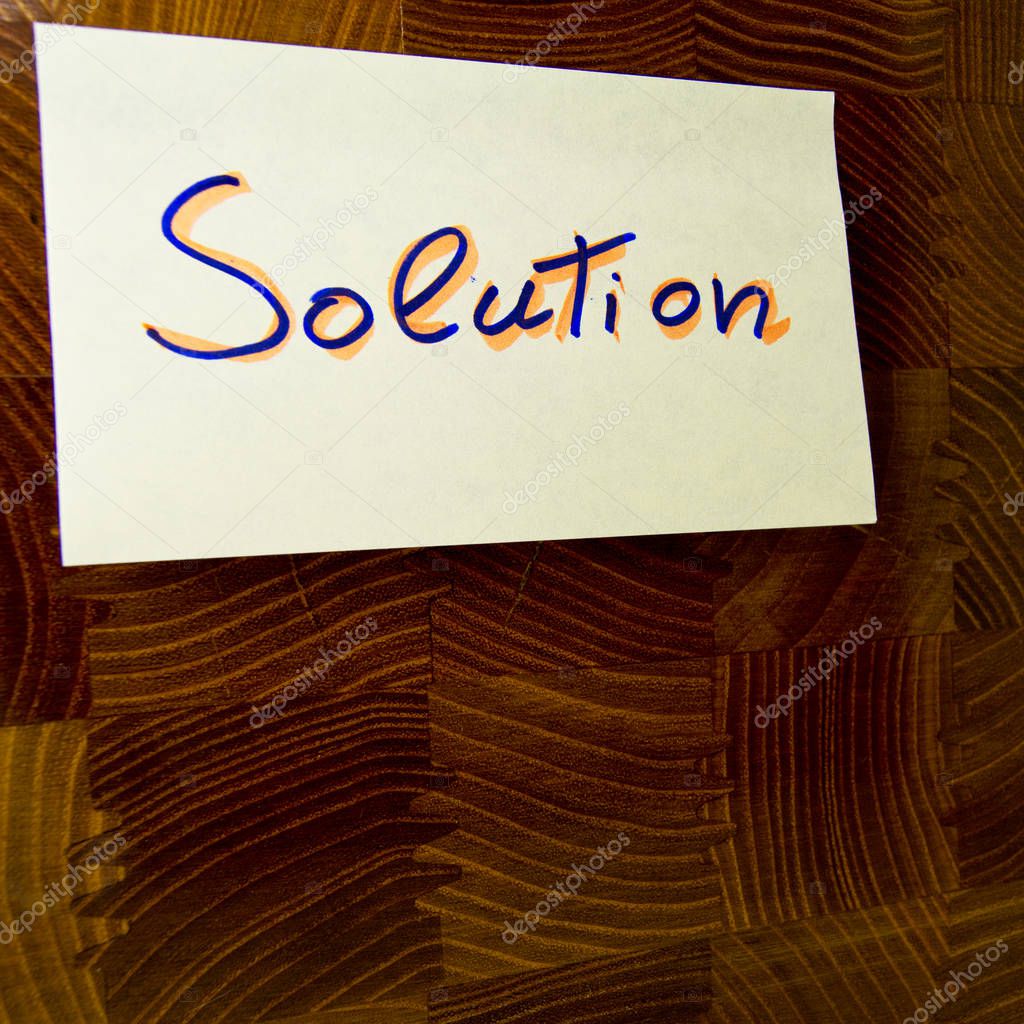word solution written on a yellow postit attached on a wood panel - for conceptual use