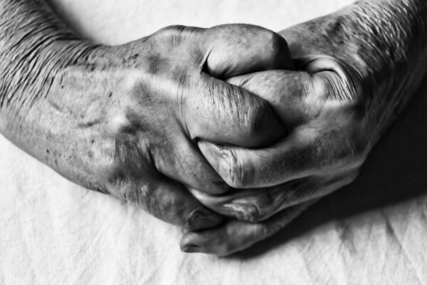 soft focus of crossed hands of an elderly woman in black and whi