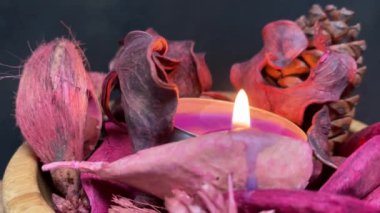 Siyah arka planı olan bir masanın üzerinde ahşap bir kâse içinde çay ve kuru potpuri.