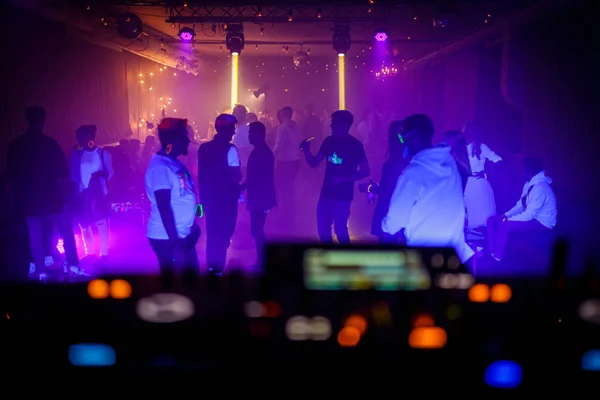 Люди танцуют на танцполе на вечеринке техно-клуба. Вид с пульта диджея . — стоковое фото