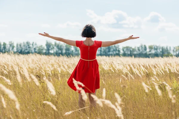 Fille en robe rouge marchant sur le terrain — Photo