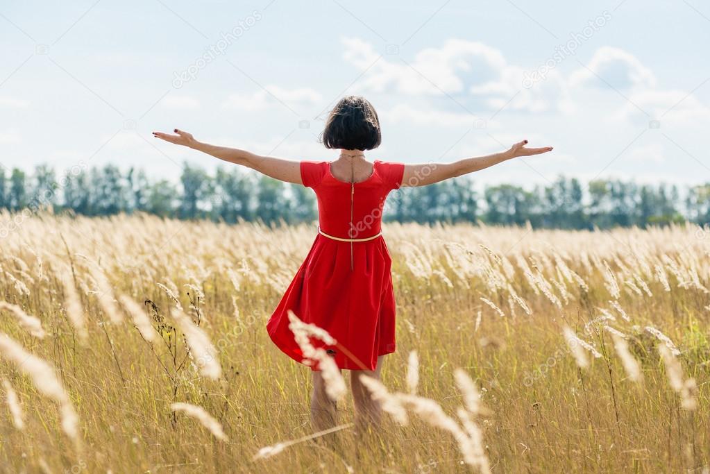 girl in red dress walking on the field