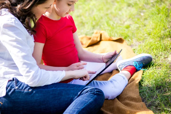 Mãe e filha usando tablet digital enquanto sentado na bela natureza , — Fotografia de Stock