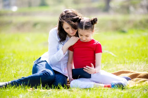 Moeder en dochter met behulp van digitale tablet zittend in de prachtige natuur, — Stockfoto