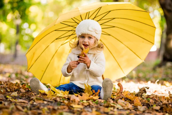 Beautiful little girl in yellow with umbrella in park — Stock Photo, Image