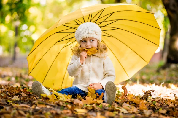 Beautiful little girl in yellow with umbrella in park — Stock Photo, Image