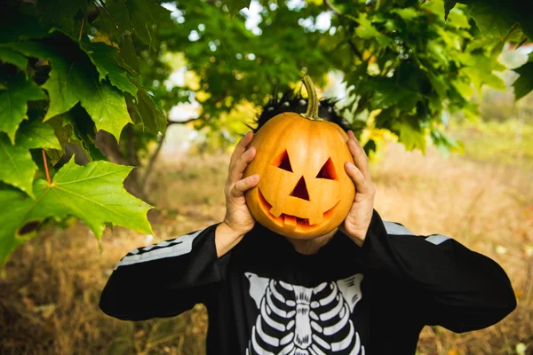 Portrait of a man in a suit holding a Halloween orange pumpkin. Skeleton. — Stock Photo, Image