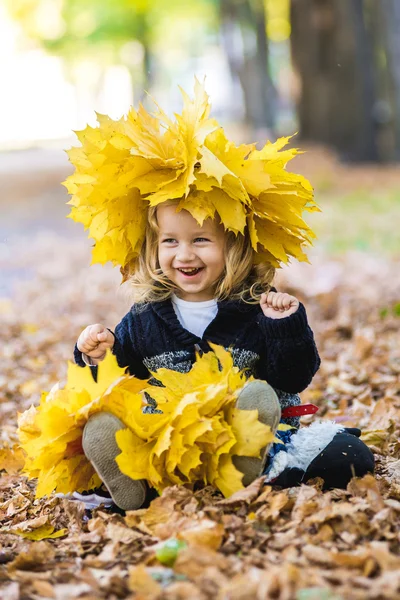 Mooi meisje in een krans van esdoorn bladeren — Stockfoto