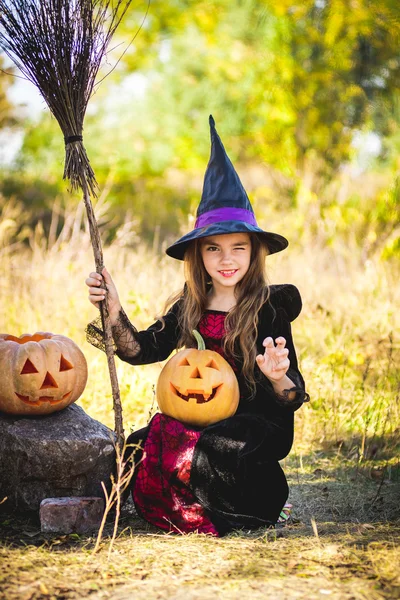 Joyeux Halloween. Petite sorcière mignonne avec une citrouille dans les mains du feu . — Photo