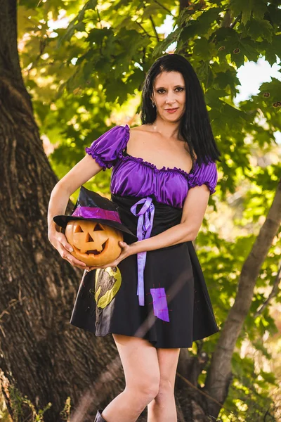 Jonge vrouw in Halloween kostuum in de herfst bos met gele pompoen witch. — Stockfoto