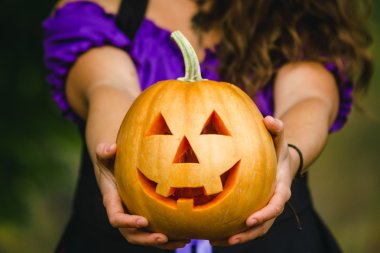 Fantezi holding Halloween ormandaki kabak oyma yüz eller kadın
