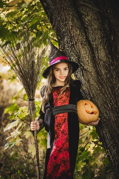 Joyeux Halloween. Petite sorcière mignonne avec une citrouille dans les mains. — Photo