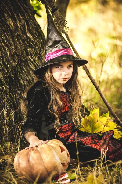 Happy Halloween. Cute little witch with a pumpkin in the hands.