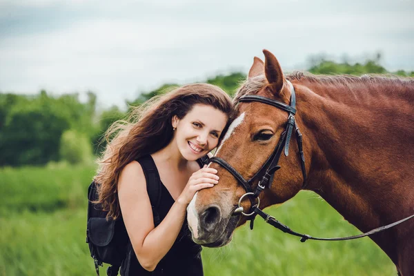 Smiling girl hugs her horse pet