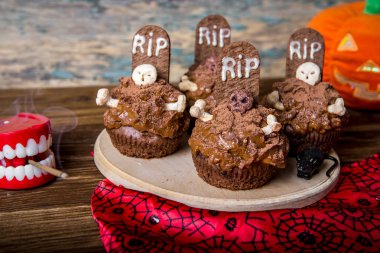Mezar taşı pasta topper ve eski bir ahşap masa mum ile Halloween cupcakes