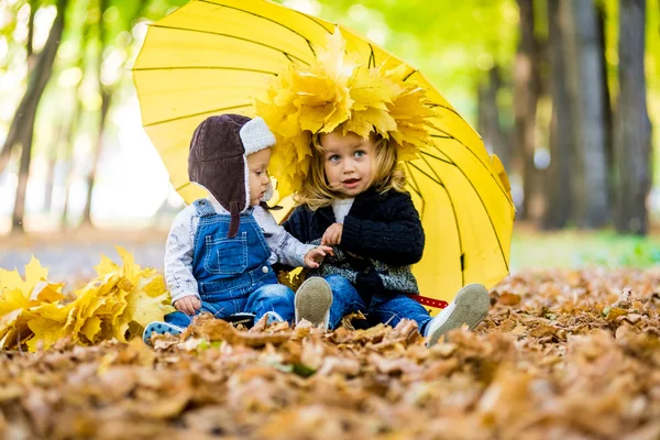 Jongetje met een meisje onder een paraplu van de herfst regen — Stockfoto
