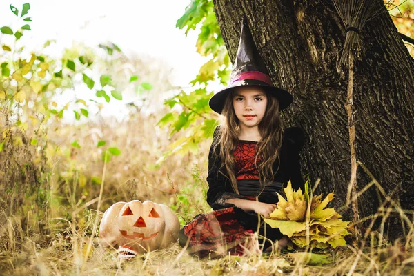 Frohes Halloween. Niedliche kleine Hexe mit einem Kürbis in den Händen. — Stockfoto