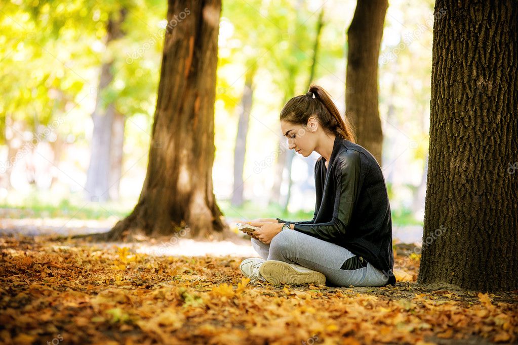 The girl with book sitting under the tree