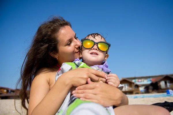 Feliz joven madre e hijo en una playa tropical con el niño risueño . — Foto de Stock