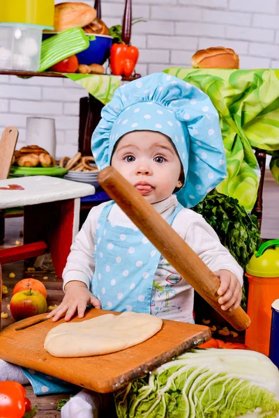 Dziewczynka w okręgu cook ubrania rolki ciasta na stół — Zdjęcie stockowe