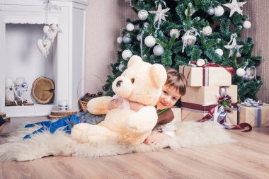 Küçük bir çocuk şöminenin yanında Noel içinde oturur.