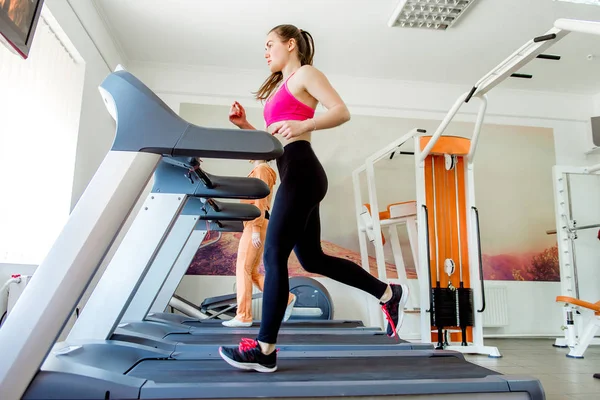 Mujer deportiva caminando en la cinta de correr en el gimnasio — Foto de Stock