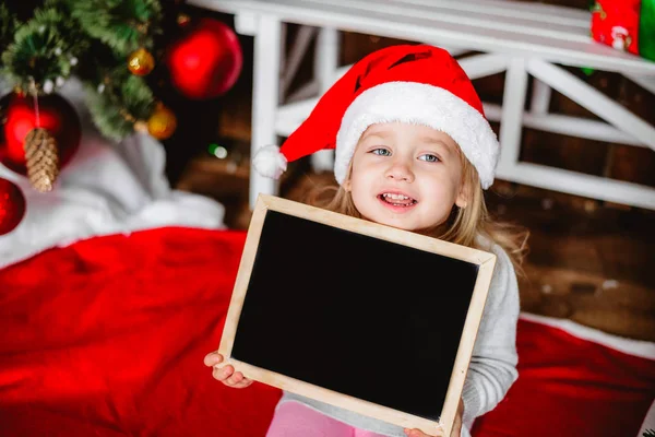 Petite fille dans le chapeau du Père Noël avec des conseils — Photo