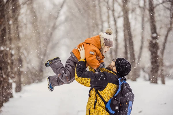 Young father playing with his baby in a snowy park. — Stock Photo, Image