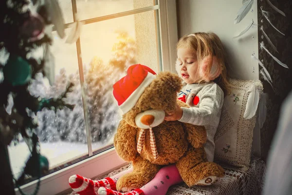 Niña feliz sentado de nuevo en la ventana de invierno Navidad — Foto de Stock