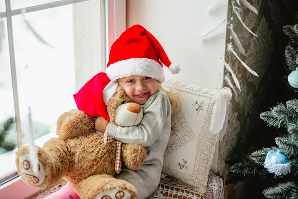 Heureuse enfant fille assis dans la fenêtre d'hiver Noël — Photo