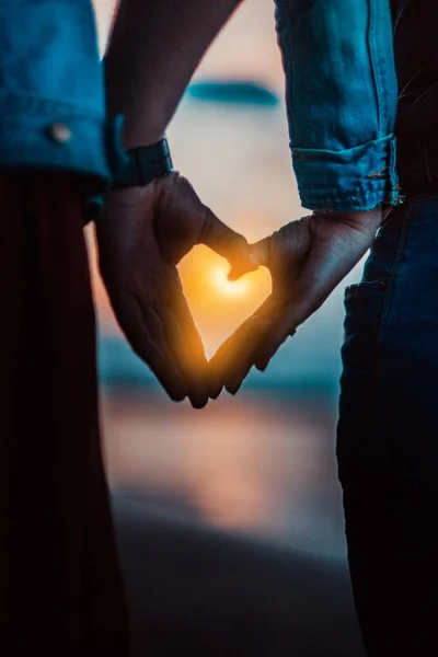 Coppia a forma di cuore con le mani sulla riva del lago. Persone silhouette foto vintage . — Foto Stock