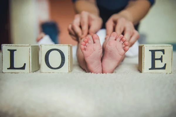 Дитячі ноги в руках матері. Крихітні ноги новонародженої дитини на жіночих руках у формі серця крупним планом . — стокове фото