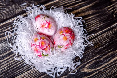 Boyalı Paskalya yumurtaları ve ahşap arka plan üzerinde çiçekler ile dekore edilmiş