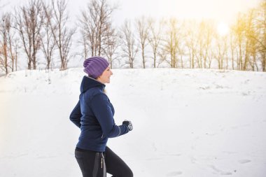 Karda koşu koşucu. Bir şehir parkında çalışan genç kadın fitness modeli