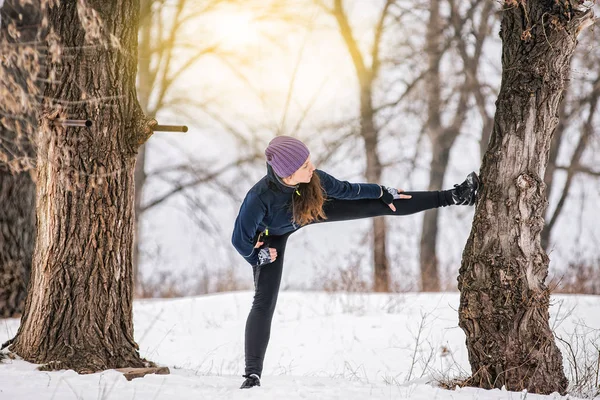 Atleta menina no inverno no parque fazendo exercícios de alongamento — Fotografia de Stock