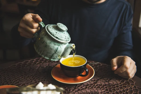 Человек наливает чай из чайника в чашку чая — стоковое фото