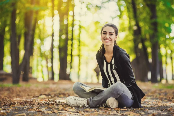 A menina com livro sentado debaixo da árvore — Fotografia de Stock